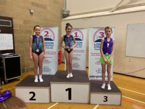 3 young trampoline gymnasts stand on a prize giving podium