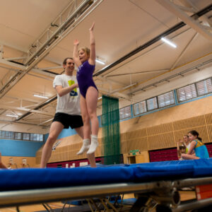 Girl learning a new skill on a trampoline with a coach
